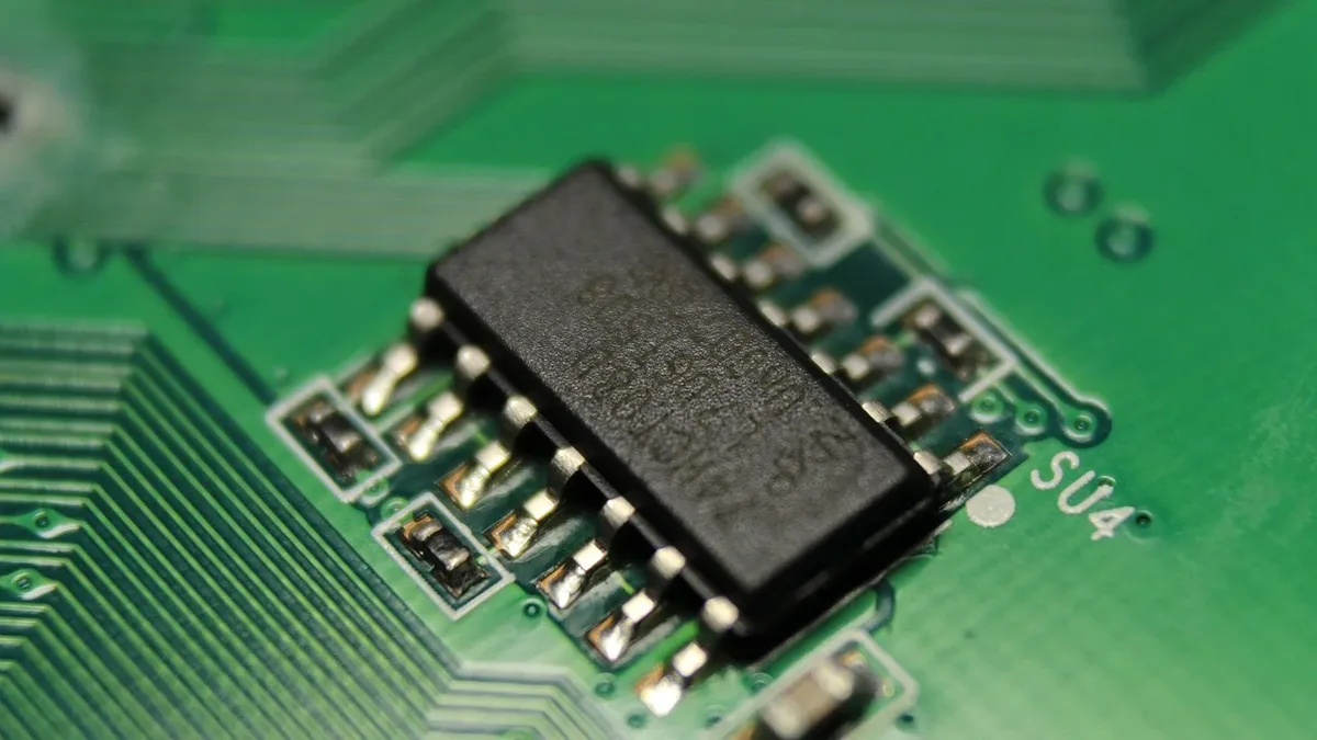 A close-up of a small electronic component on a green circuit board.